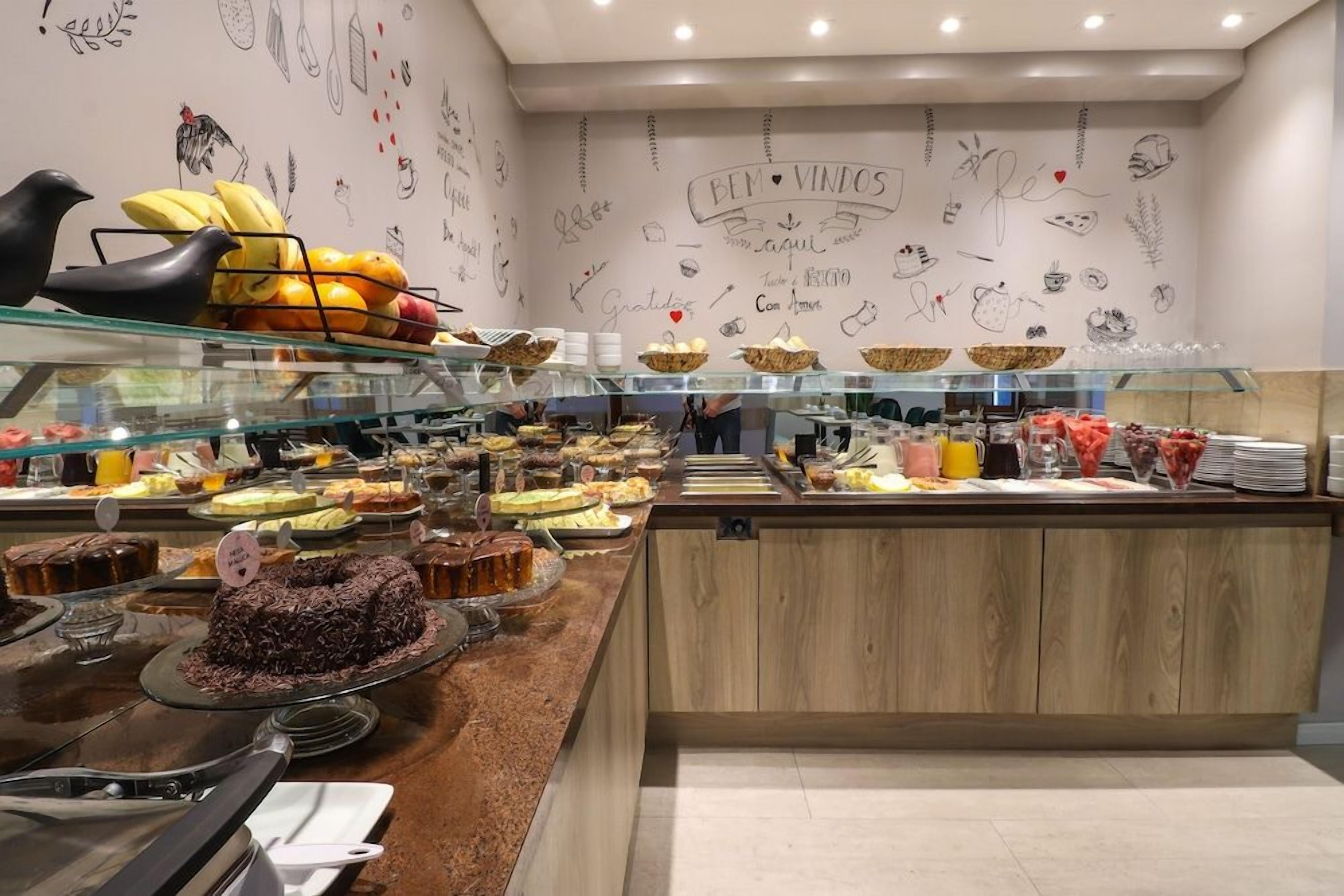 A bakery counter with various baked goods and a wall decorated with food-related drawings and text.
