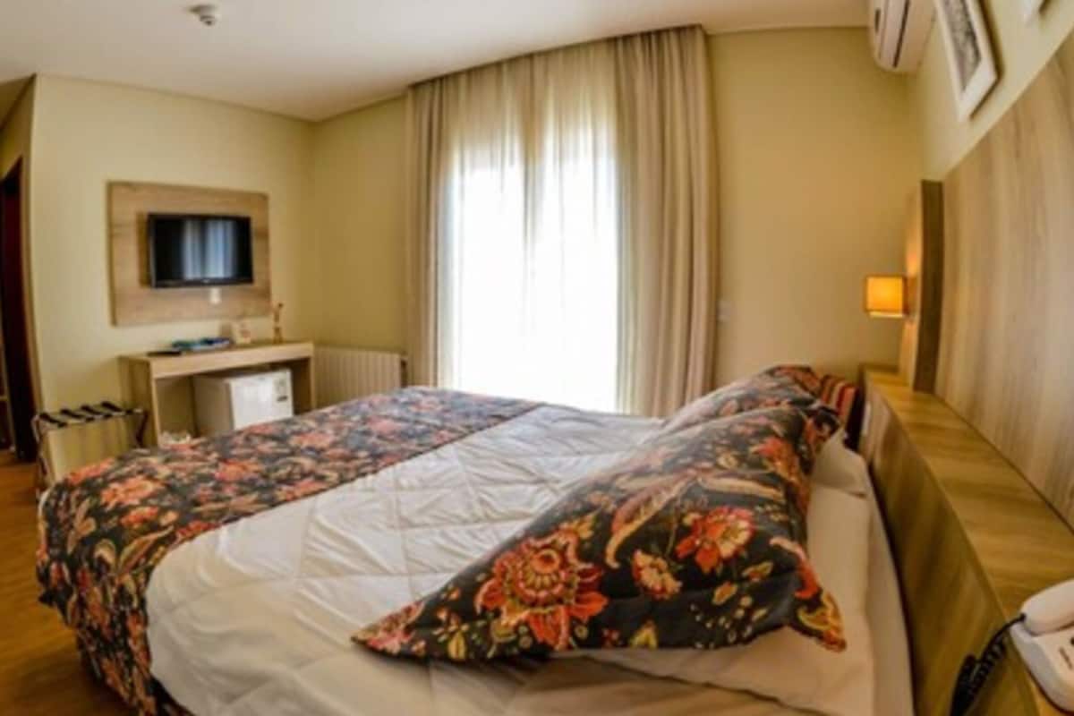 Hotellihuone, jossa on sänky, työpöytä, televisio ja puhelin.