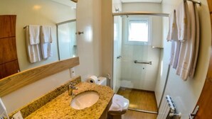 A bathroom with a granite sink, a mirror, a toilet, and a shower. - Pousada Aconchego da Borges (Gramado)