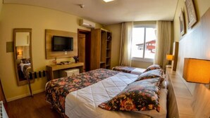 A hotel room with two beds, a TV, a desk, and a window with curtains. - Pousada Aconchego da Borges (Gramado)
