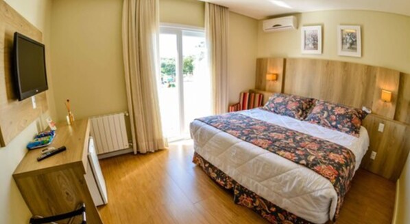 A bedroom with a bed, a desk, a TV, and a window with curtains. - Pousada Aconchego da Borges (Gramado)