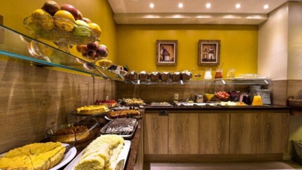 A buffet with various food items and beverages, including fruits, pastries, and a glass display case. - Pousada Aconchego da Borges (Gramado)