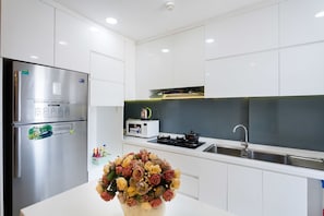 Uma cozinha moderna com armários brancos, geladeira de aço inoxidável, micro-ondas e fogão a gás.