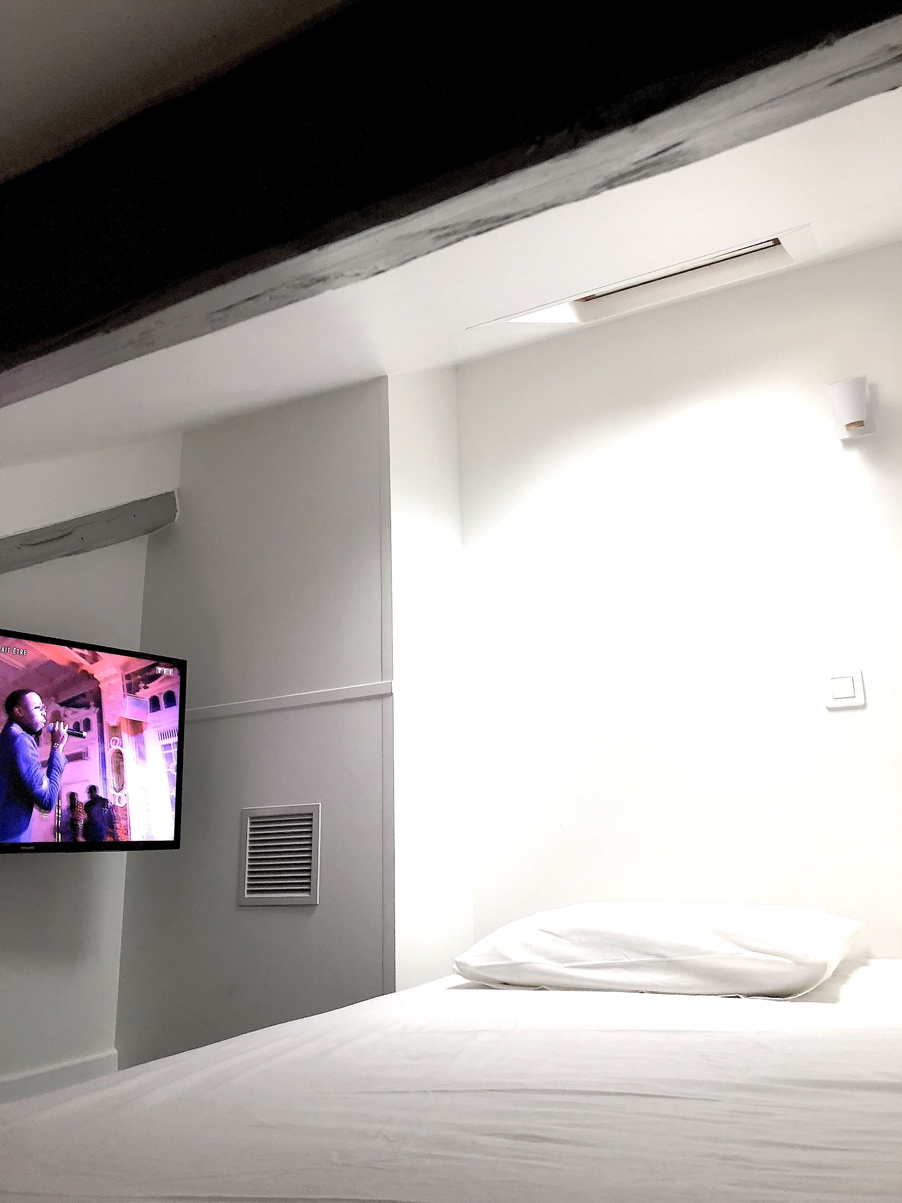 Une chambre d’hôtel équipée d’un lit, d’un téléviseur fixé au mur et d’un climatiseur mural.