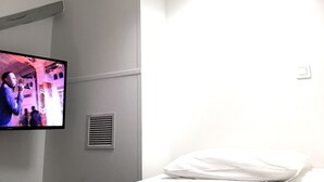 Habitació d'hotel amb llit, televisió penjada i aire condicionat fixat a la paret.