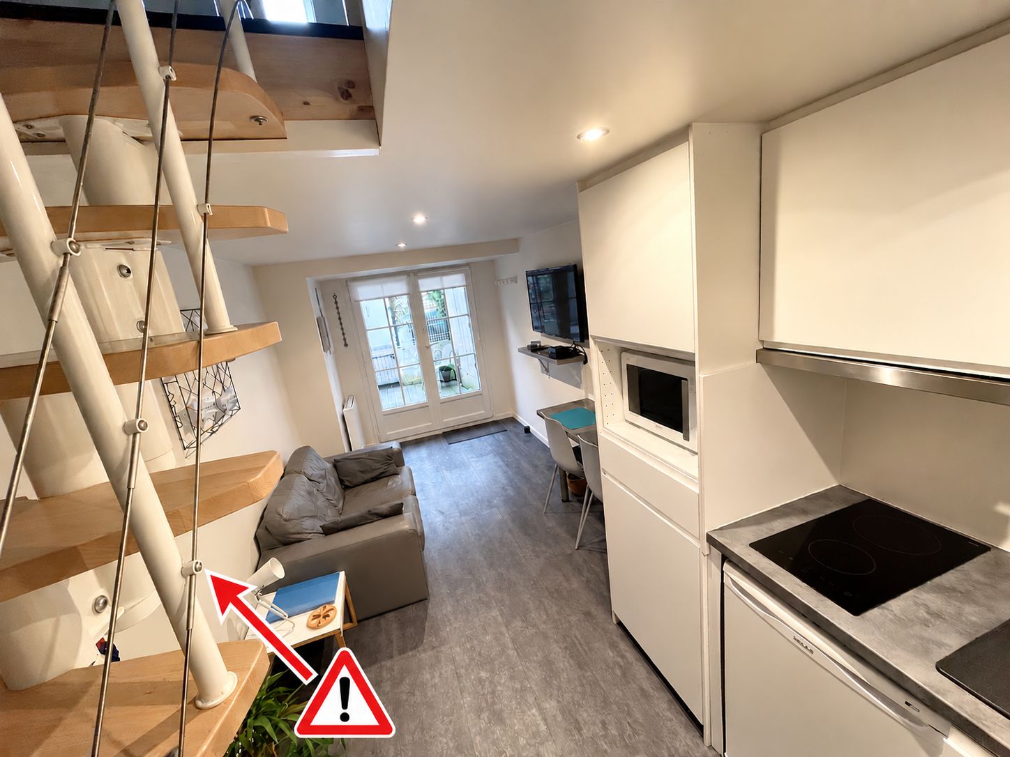 Een moderne keuken met een inbouwfornuis, een eethoek met een tafel en stoelen, en een trap met uitzicht op de woonkamer.