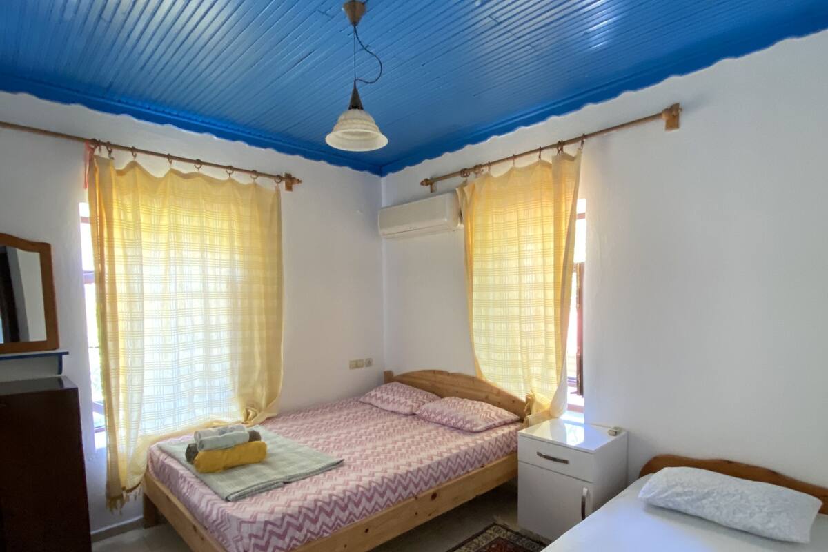 A room with two beds, a wooden headboard, a nightstand, a desk, a chair, and a patterned rug.