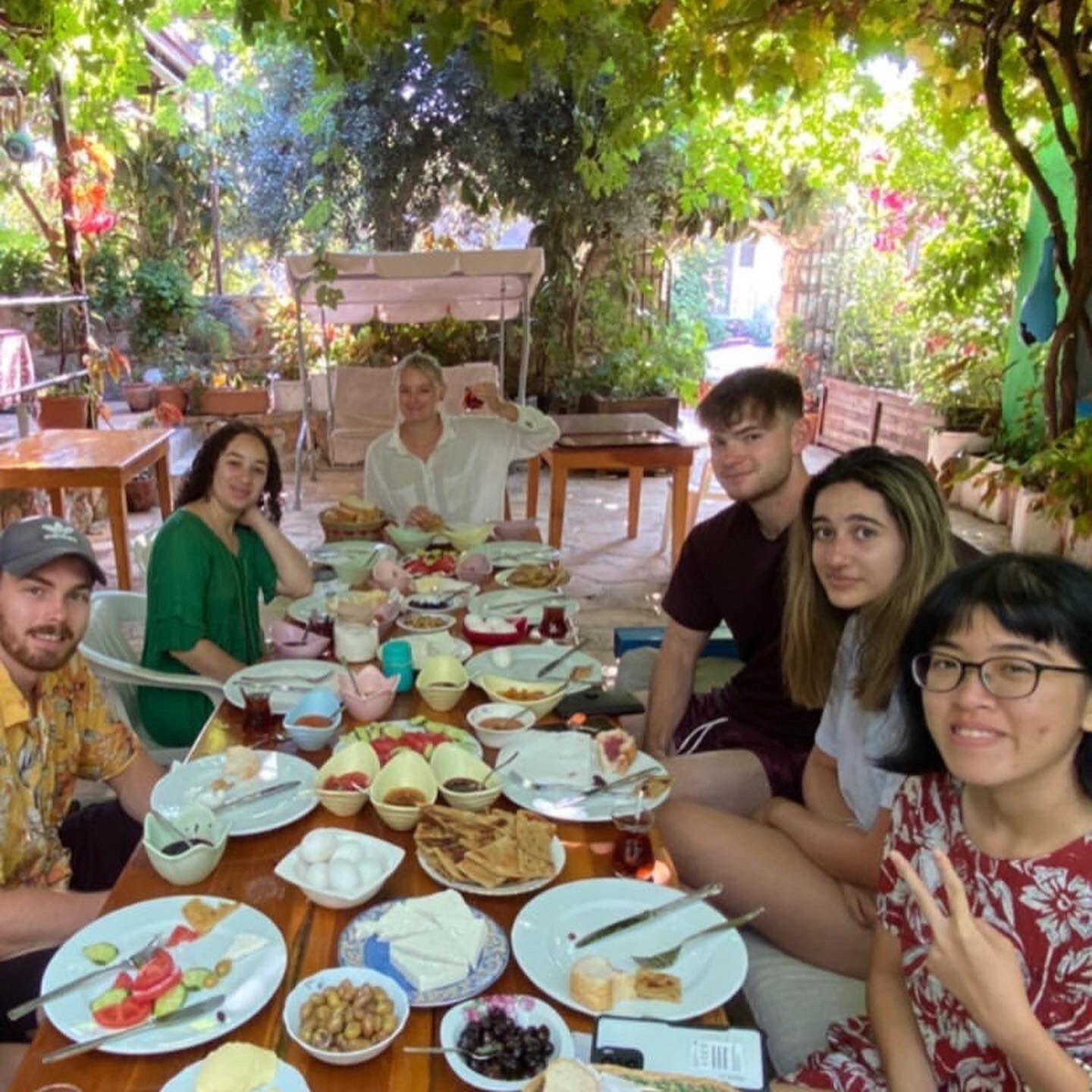 A group of people dining outdoors at a table with various dishes and drinks.