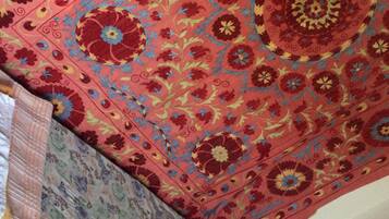 Una cama con colcha estampada de flores y una almohada lisa.