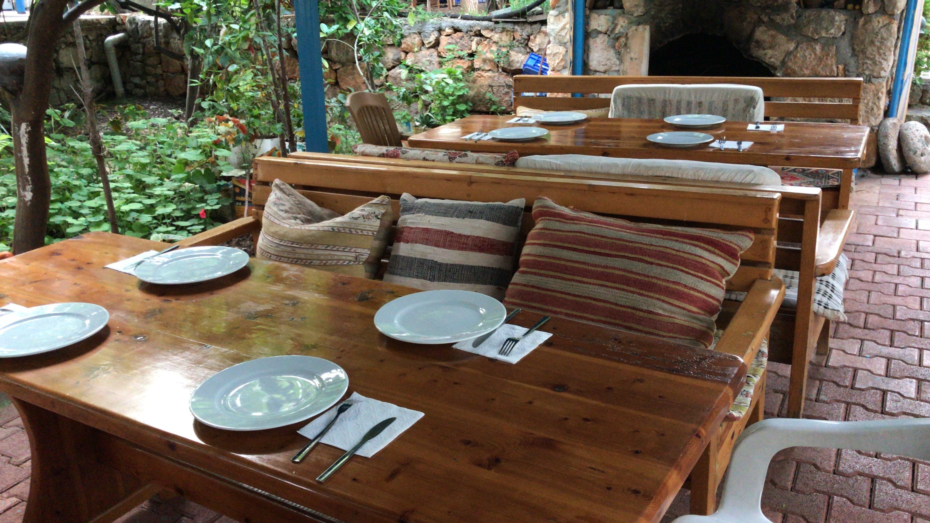 Una mesa de comedor de madera dispuesta con platos, cubiertos y una servilleta.