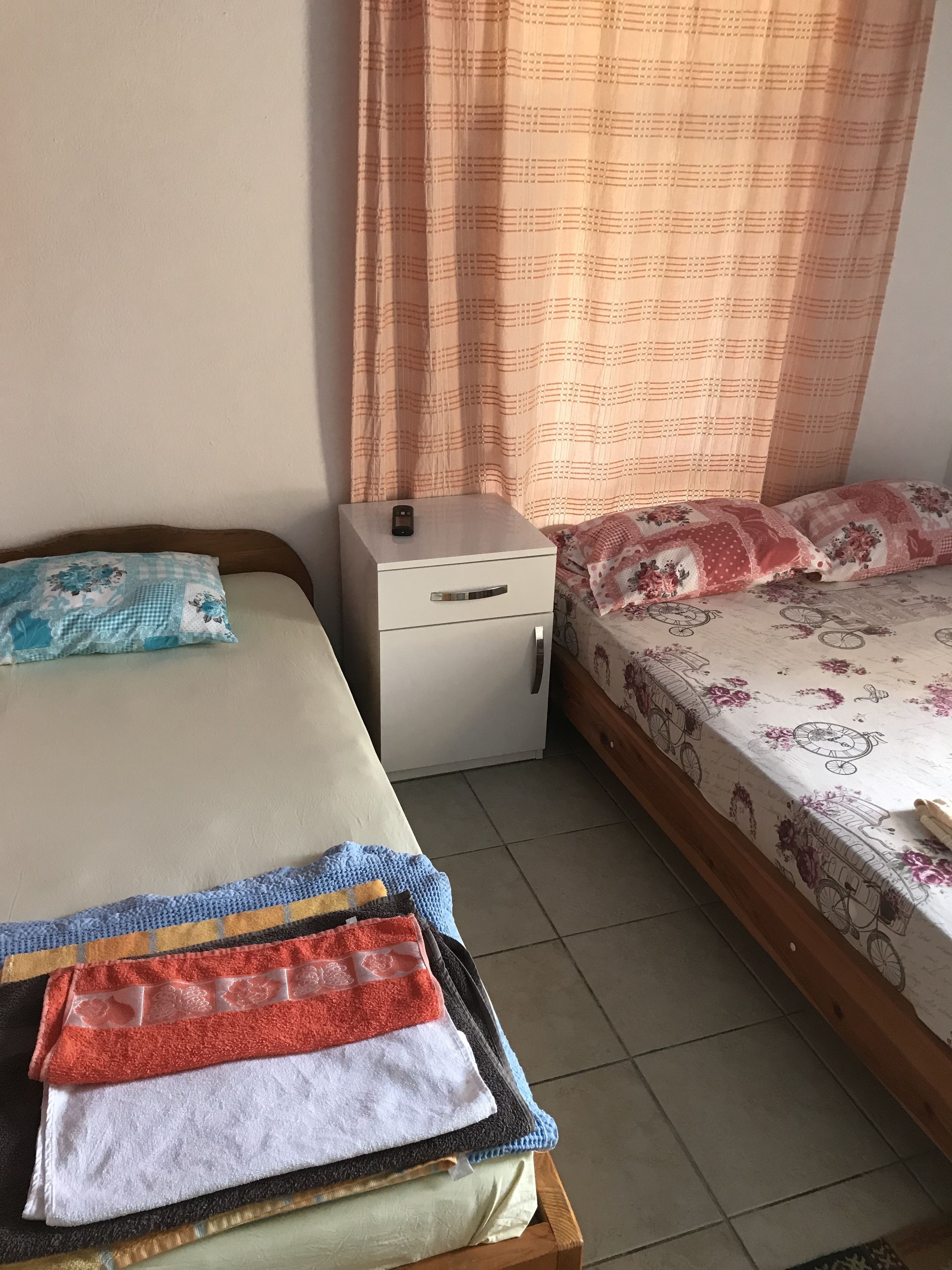 Une chambre avec deux lits, une table de chevet et une petite table avec des serviettes.
