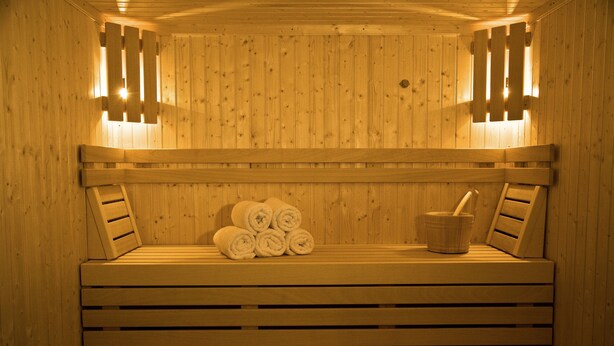A wooden sauna with benches, towels, and a bucket.