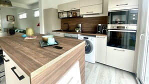 Une cuisine moderne dotée d’un plan de travail en bois, d’appareils électroménagers intégrés et de meubles de rangement blancs.