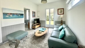 Un salon avec un canapé, une table basse, un téléviseur et des œuvres d’art accrochées aux murs.