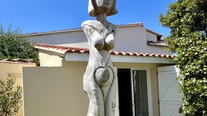 Une sculpture dans un jardin, avec une maison en arrière-plan.