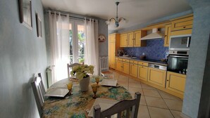 A kitchen with yellow cabinets, a dining table with a vase of flowers, and a window with curtains.