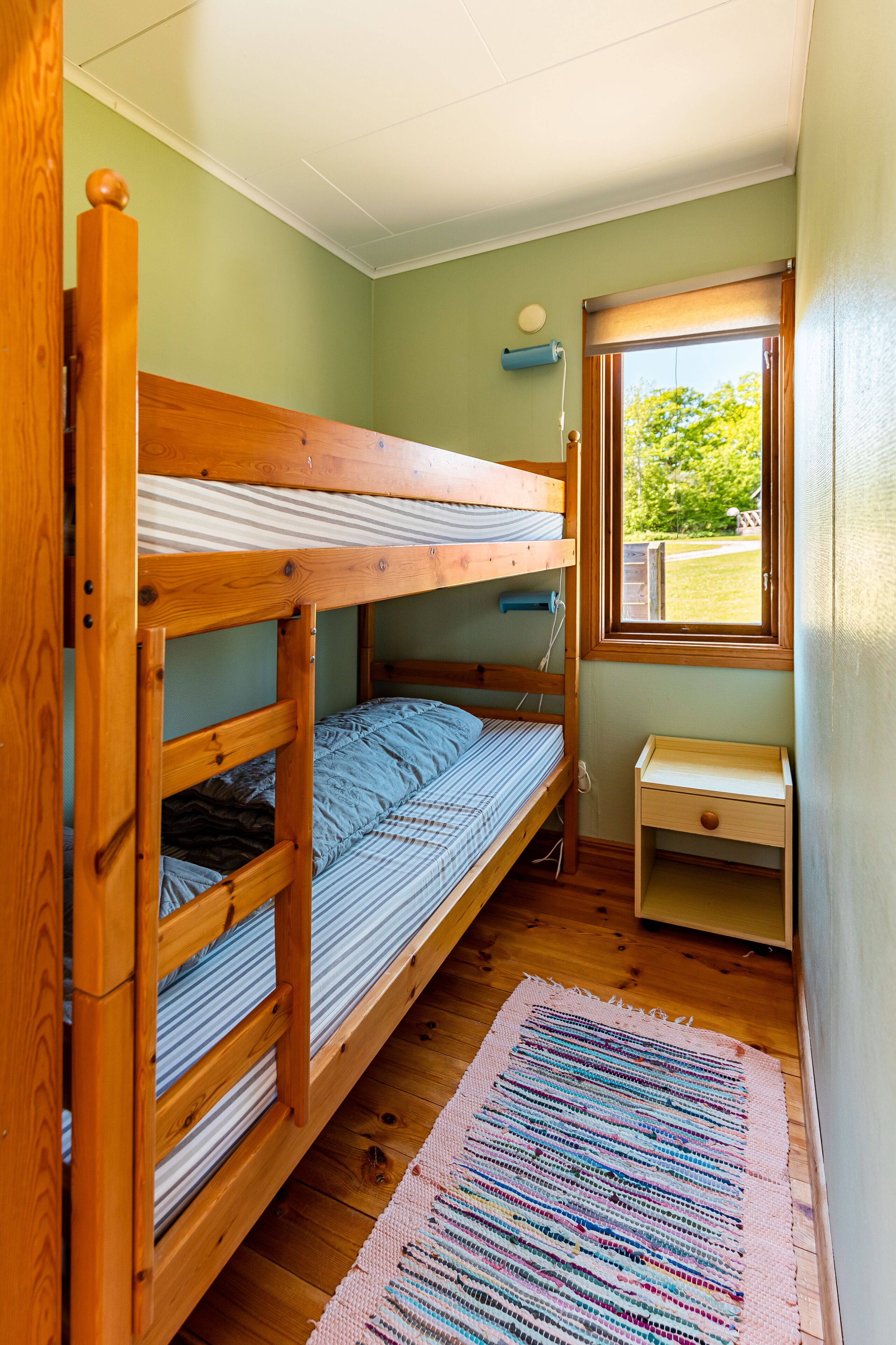 A bunk bed room with a small desk and a window.