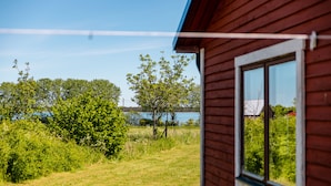 A wooden cabin with a window overlooking a grassy area and trees. - Fårösunds Semesterby (Fårösund)