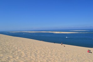 Una playa arenosa con cielo azul despejado y mar tranquilo.