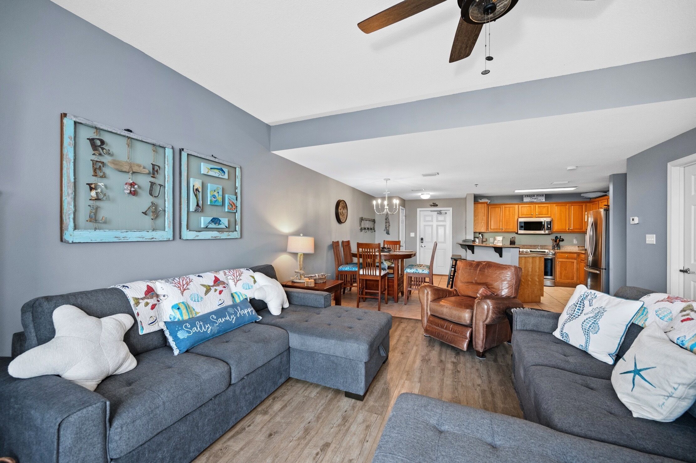 A living room with grey sofas, a coffee table, and a dining area with a table and chairs.