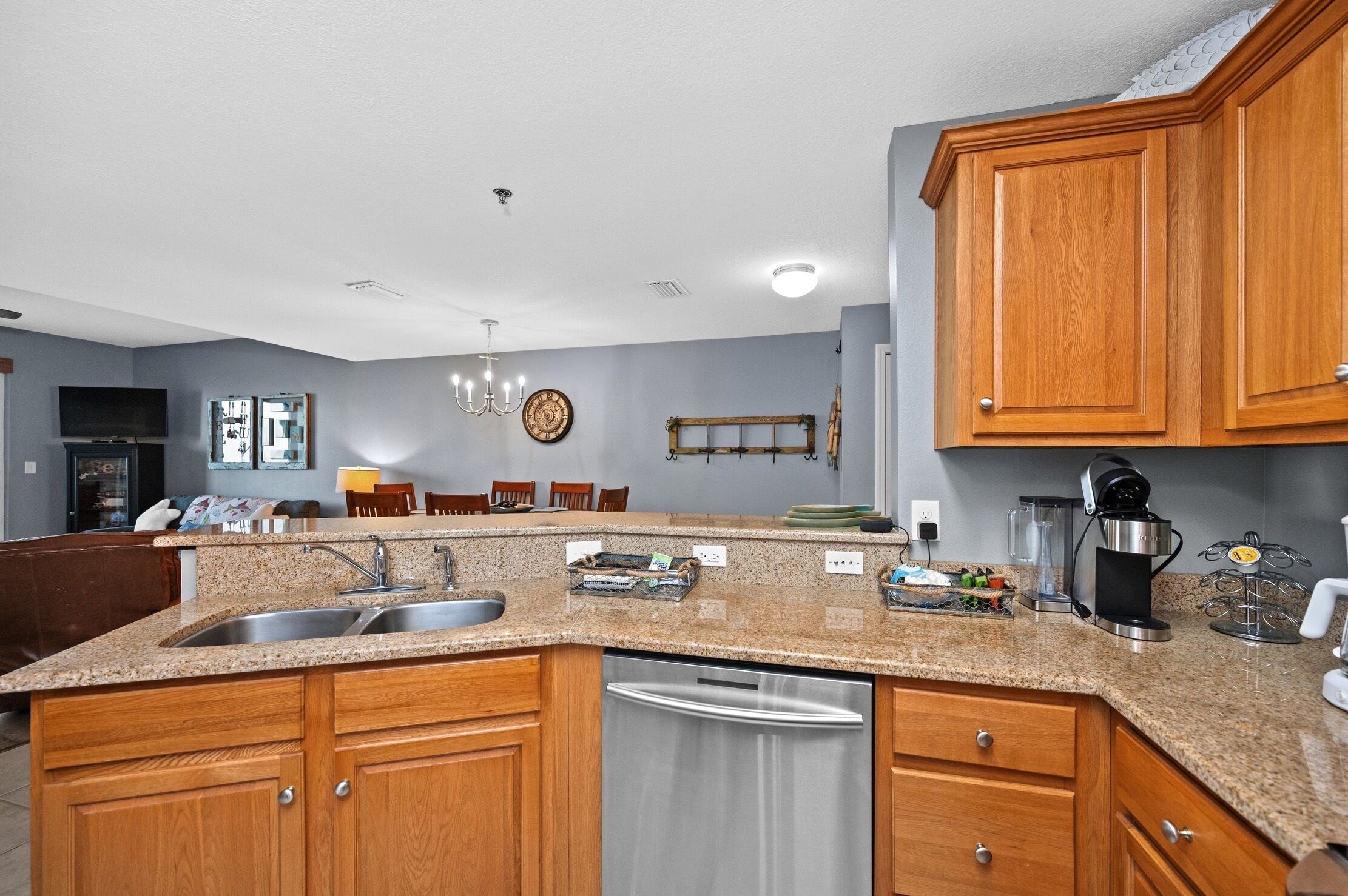 A kitchen with granite countertops, wooden cabinets, stainless steel appliances, and a dining area with chairs and a table.