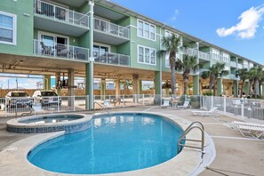 A hotel with a swimming pool, multiple balconies, and outdoor seating areas.