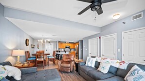 A living room with a sofa, armchair, and a dining area with chairs and a table.