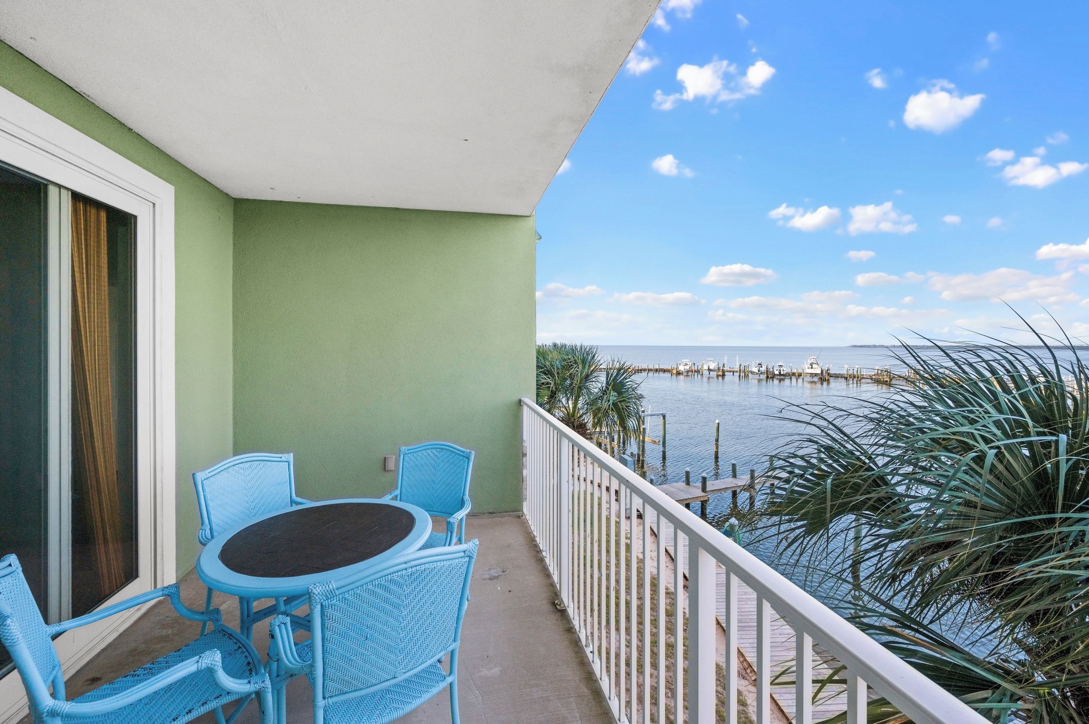 Ein Balkon mit Tisch und Stühlen, mit Blick auf ein Gewässer und einen Steg.