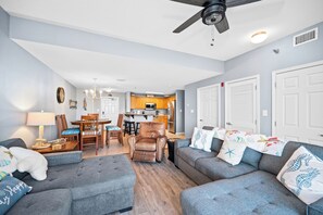 A living room with a sofa, armchair, and a dining area with chairs and a table.