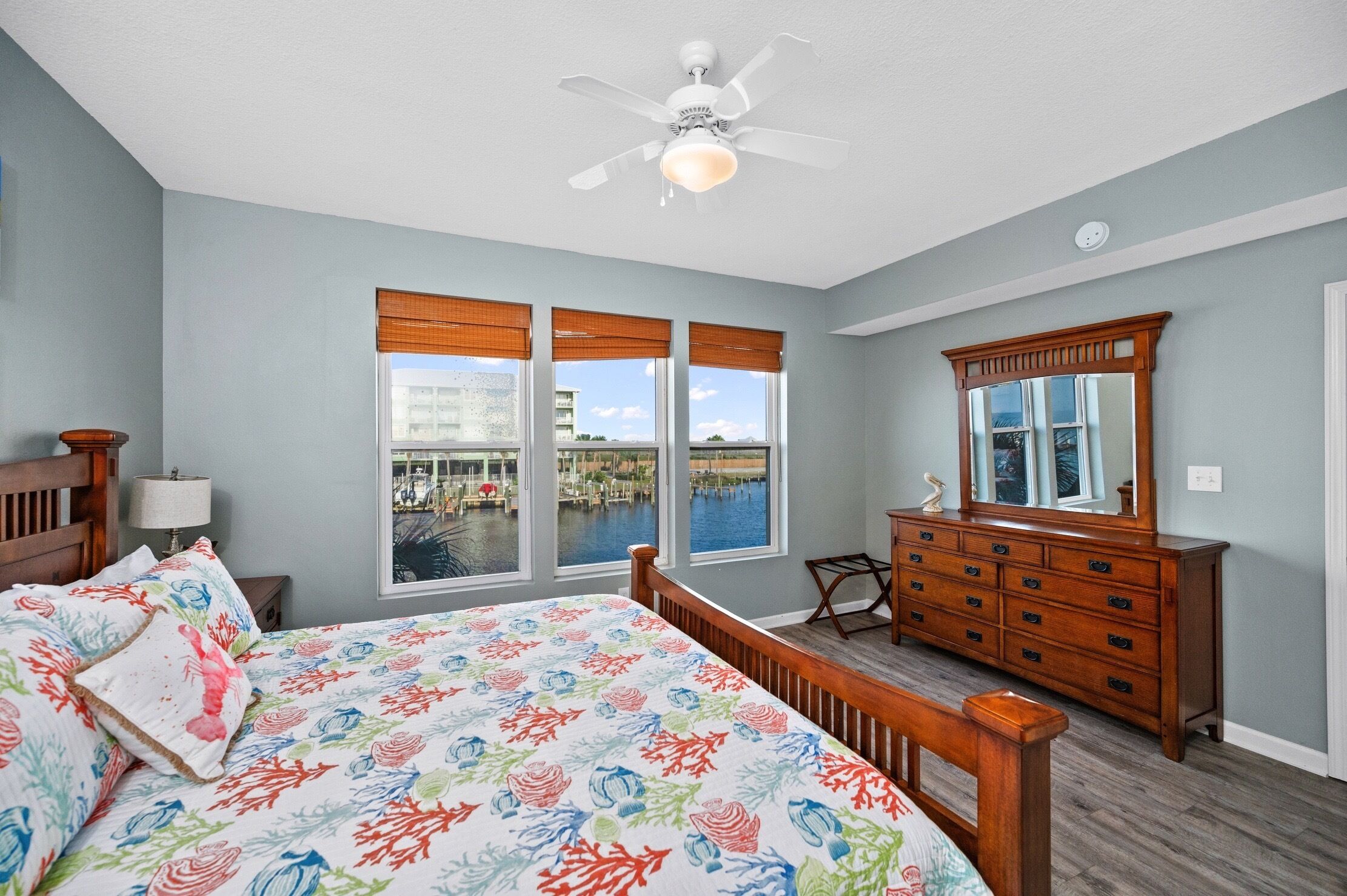 A bedroom with a large bed, a dresser, a mirror, and a ceiling fan.