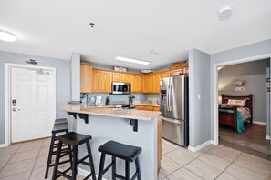 A kitchen with wooden cabinets, a stainless steel refrigerator, and a granite countertop.