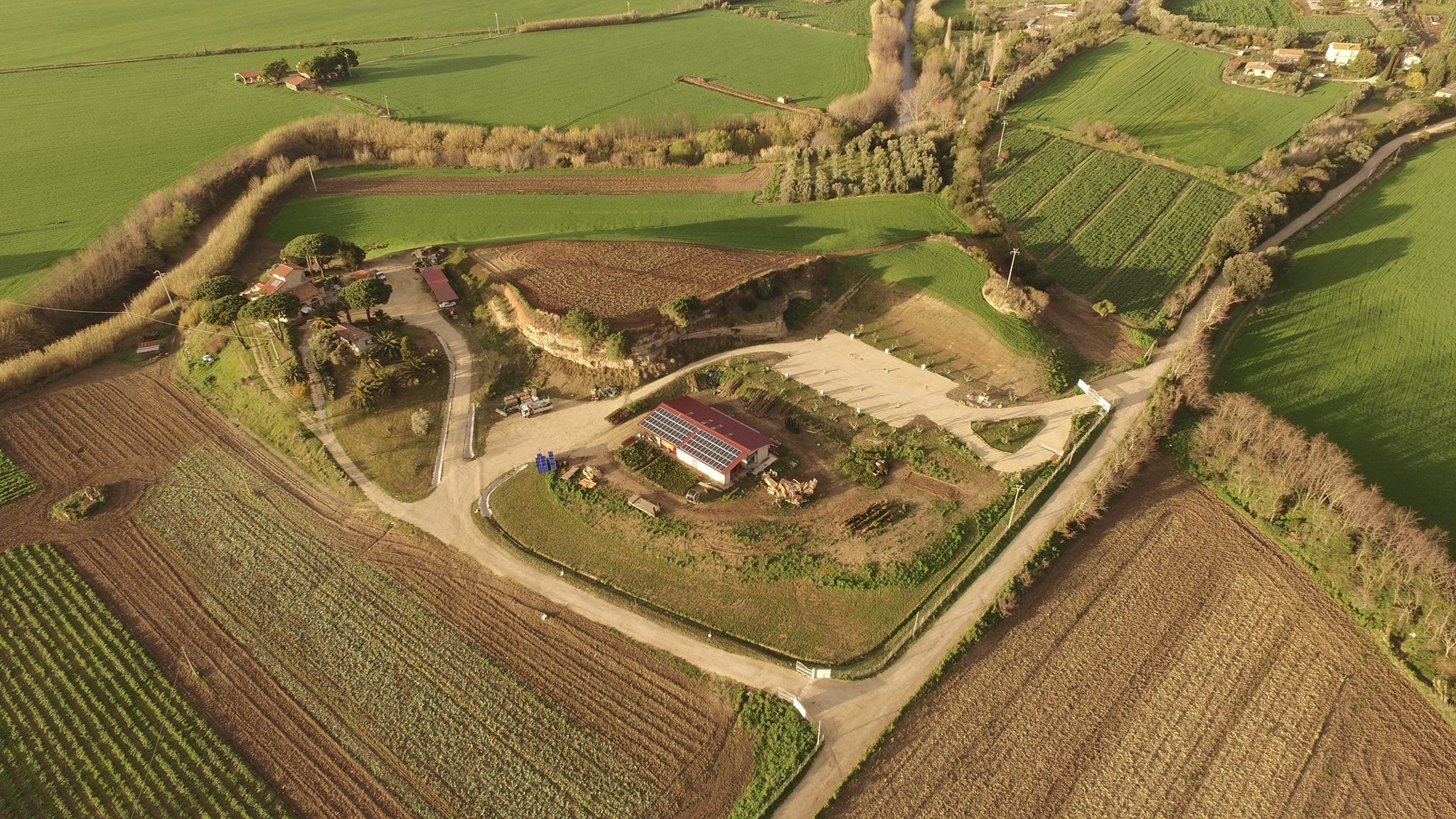 Vista aérea de una propiedad rural con campos, una casa de campo e instalación de paneles solares.