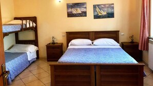 A bedroom with a bunk bed, a double bed, two bedside tables, and two wall-mounted paintings of sailboats. - Agriturismo Il Poderino (Tarquinia)