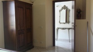 A hallway with a wooden wardrobe, a mirror on the wall, and a door leading to another room. - Agriturismo Il Poderino (Tarquinia)