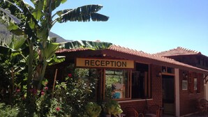 A reception area with a sign, potted plants, and wicker furniture.