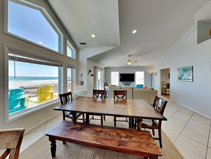 Relax in this spacious living area with a large dining table and comfortable seating, offering a stunning view of the beach.