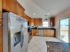 Enjoy cooking with a view of the ocean from this kitchen, featuring a refrigerator, oven, and dishwasher.