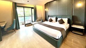 A modern hotel room with a large bed, a seating area with a chair, a small table, and a view through the window. - Comfort Inn Silver Arch Hotel, Mussoorie (Dehradun)