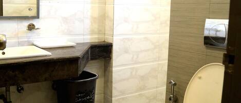 A bathroom with a toilet, sink, mirror, towel rack, and trash can.