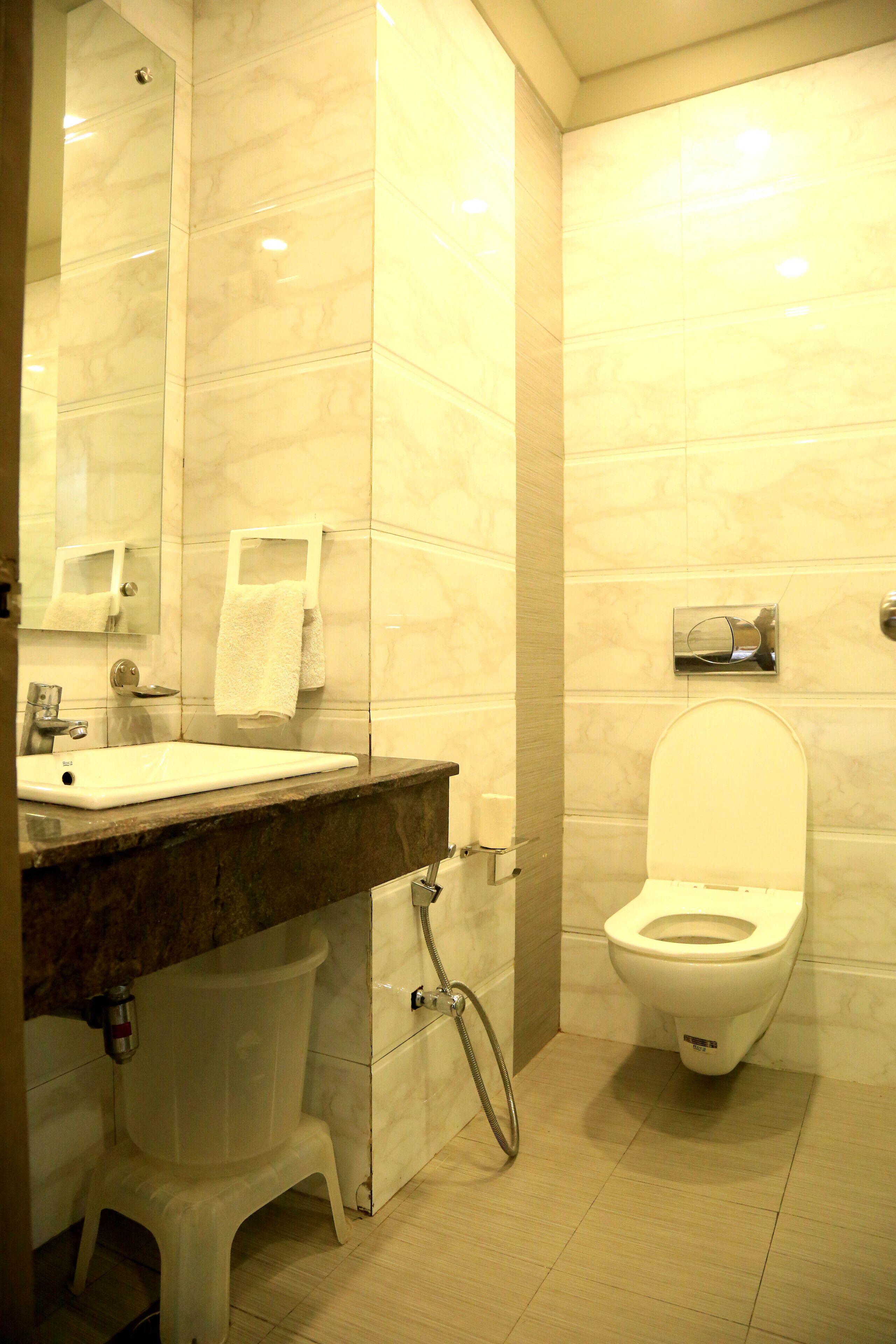 A bathroom with a marble sink, a toilet, and a mirror.