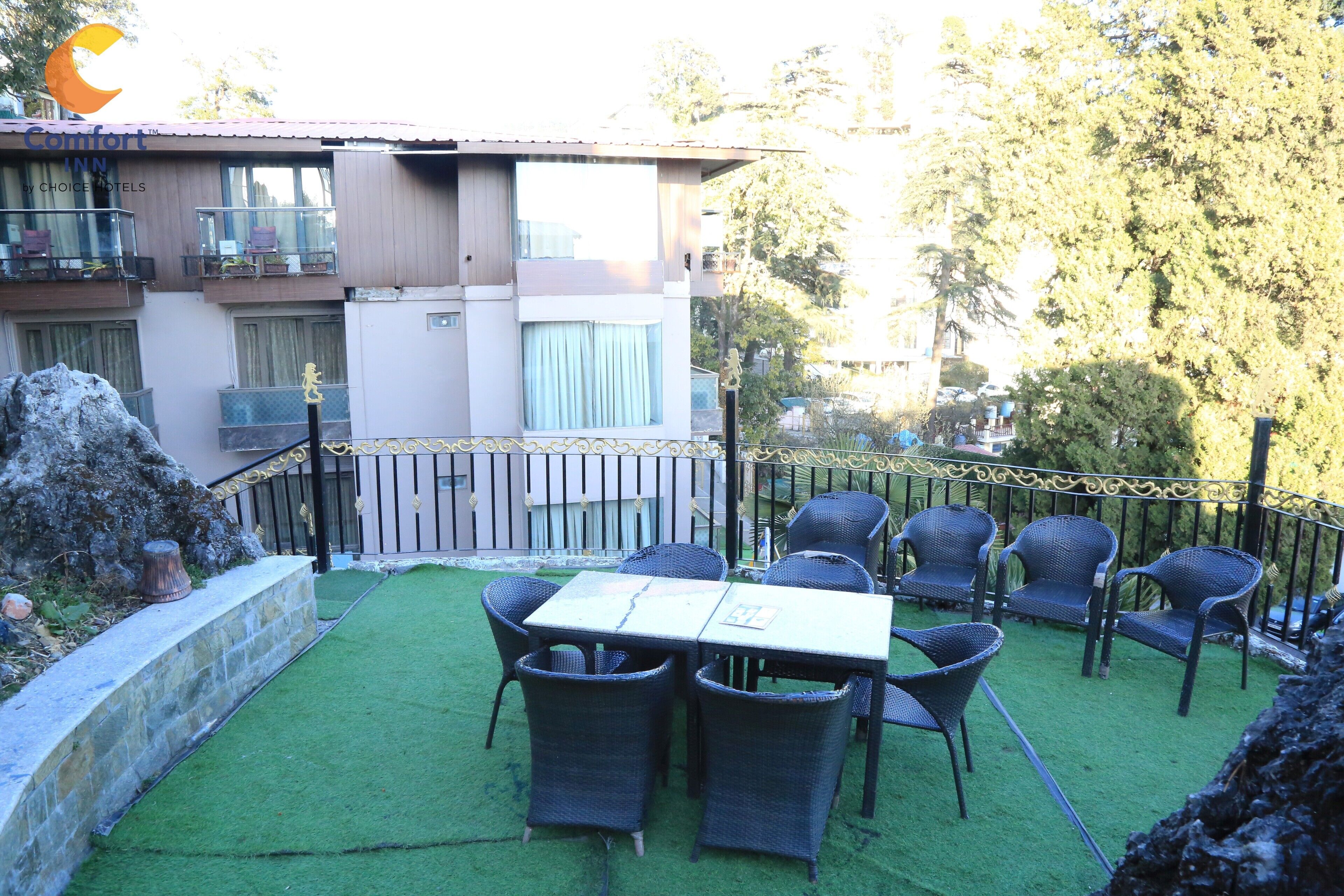 An outdoor patio with a table and chairs, a stone wall, and a building with balconies in the background.