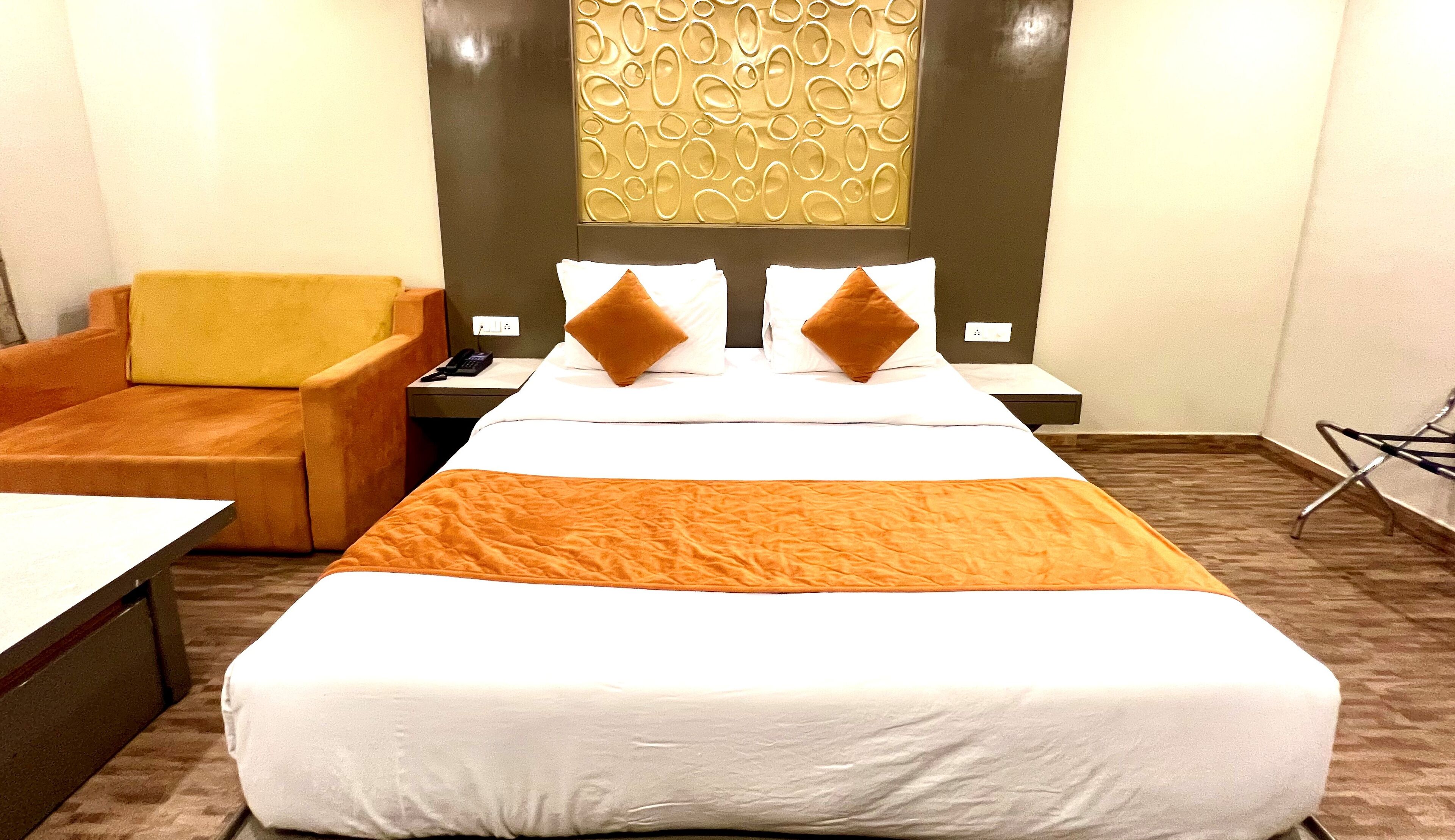 Camera d'albergo con un letto grande, due cuscini, un comodino, una sedia e un pannello decorativo a parete.