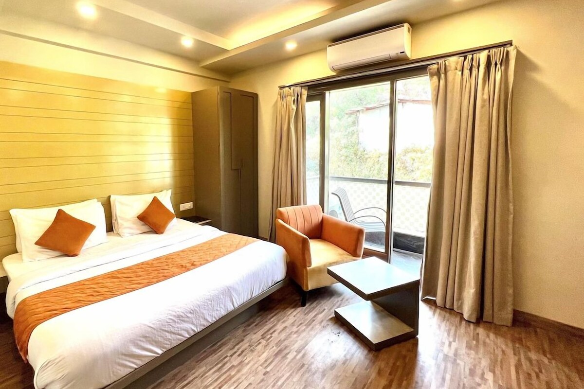 A hotel room with a bed, a sofa, a small table, and a window with curtains.