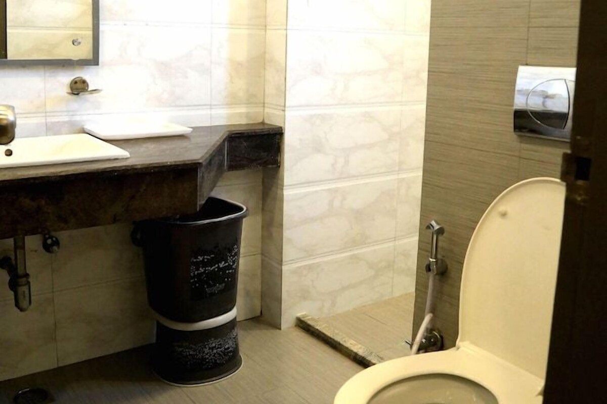 A bathroom with a toilet, sink, mirror, and towel rack.