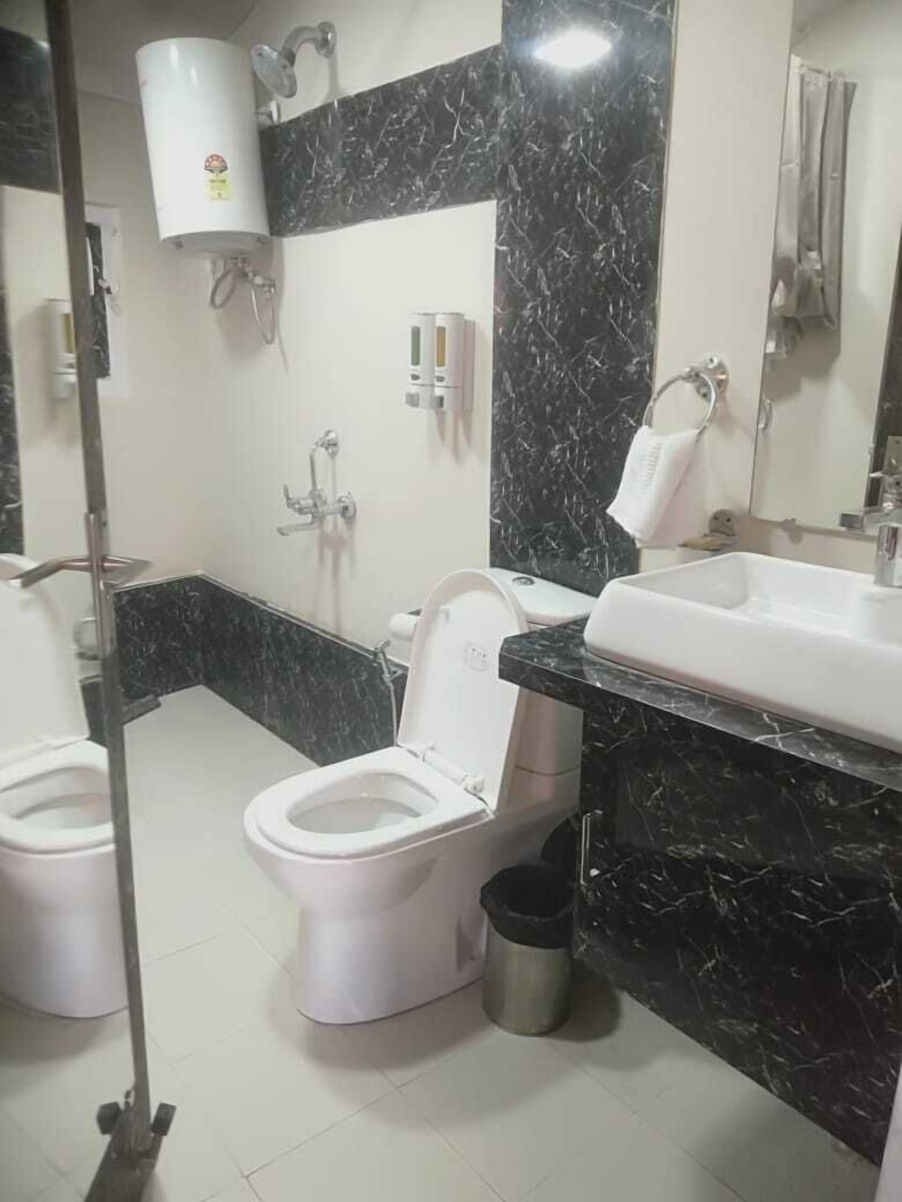 Baño con dos inodoros, un lavabo, un espejo y una ducha.