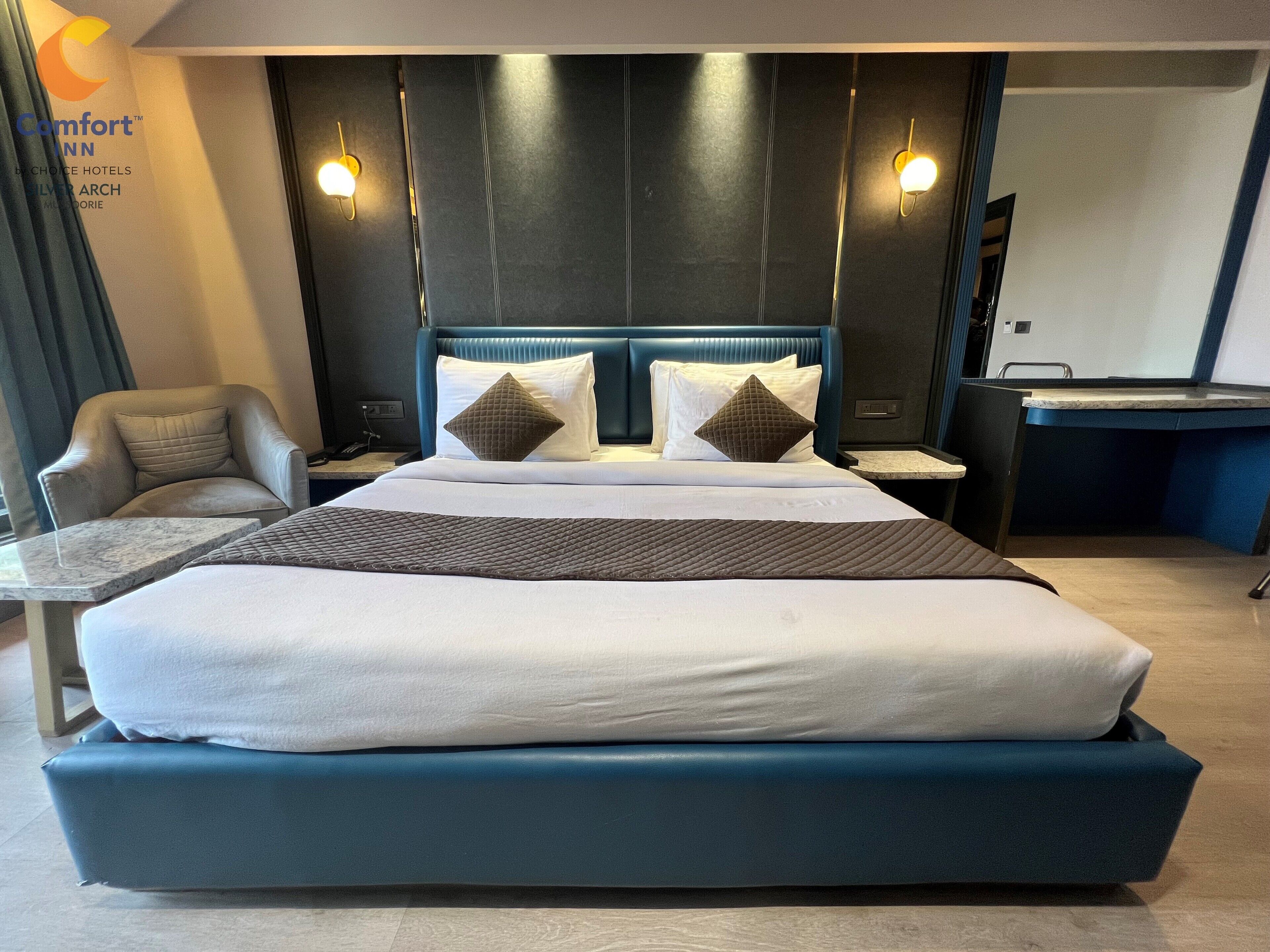 A hotel room with a large bed, two bedside tables, a chair, a desk, and a mirror.