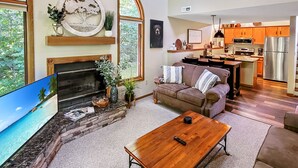 Ein geräumiges Wohnzimmer mit Kamin, Fernseher und einer gemütlichen Sitzecke.