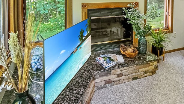 Ein Wohnzimmer mit Kamin, großen Fenstern und einem Flachbildfernseher.