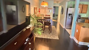 A modern kitchen with dark wood cabinetry, a dining area with a table and chairs, and a hallway leading to other rooms. - Luxurious King bed Condo across from Beach, Boardwalk, Shops and Restaurants.  (Biloxi)
