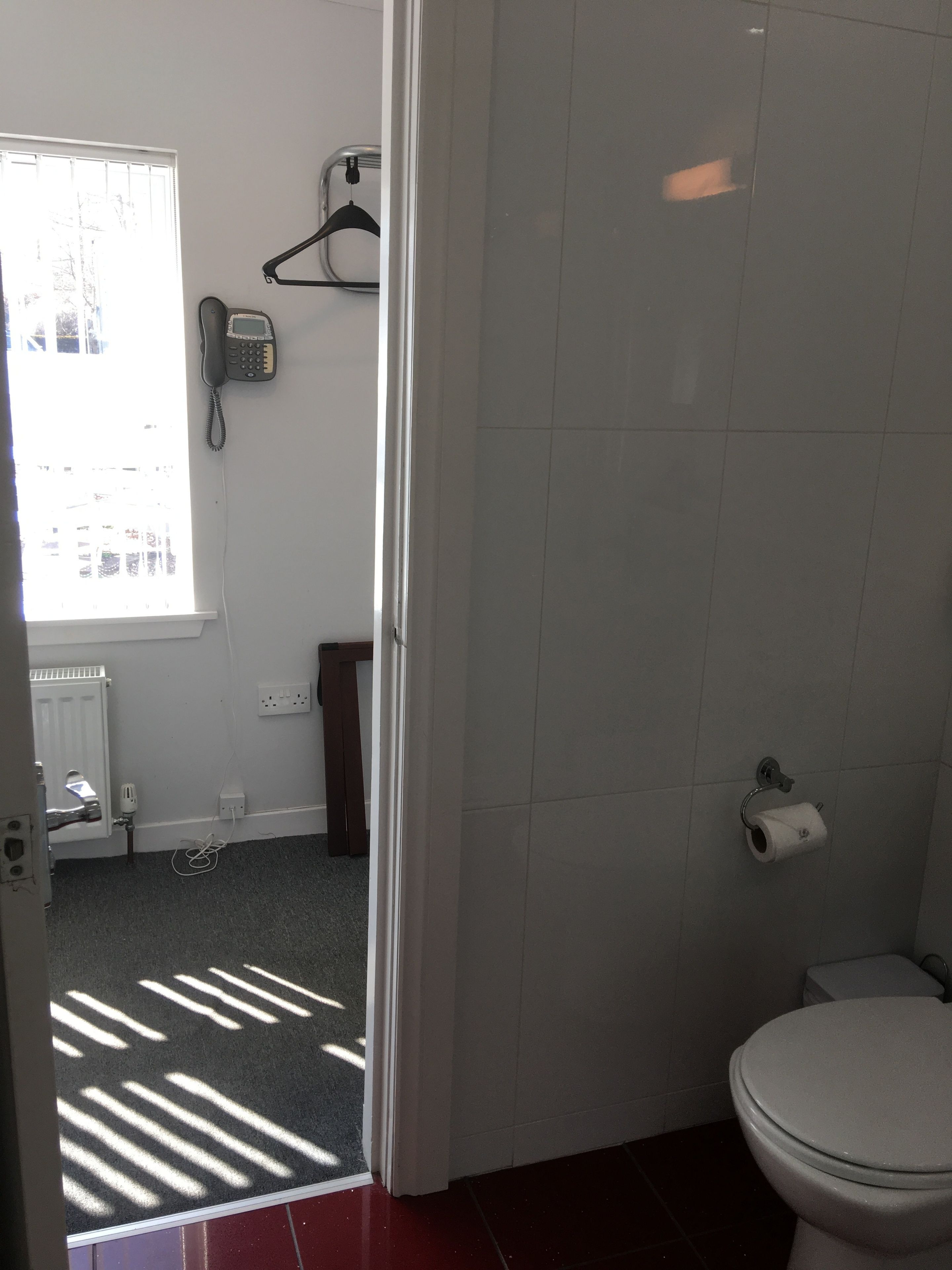 Een badkamer met toilet, handdoekhouder, radiator en raam.